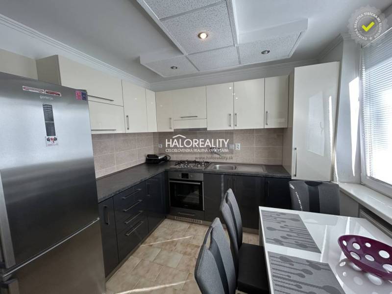 A kitchen in a 2-room apartment with a wood-patterned floor and light cabinets.