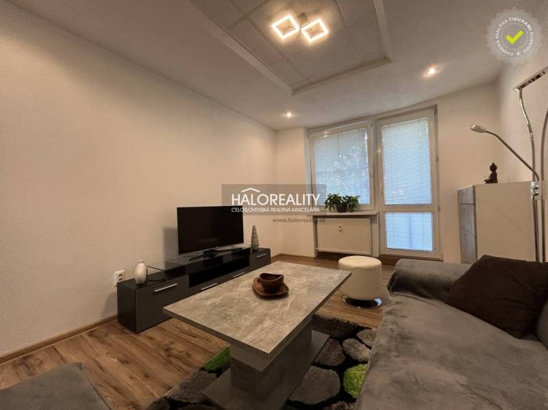 Living room in a two-room apartment with a wooden decor floor and a television.