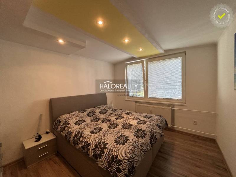 Bedroom in a two-room apartment with a wooden decor floor and a large upholstered bed.