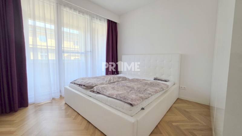 Bedroom in a 2-room apartment with a bed, curtains, and a wooden decor floor.