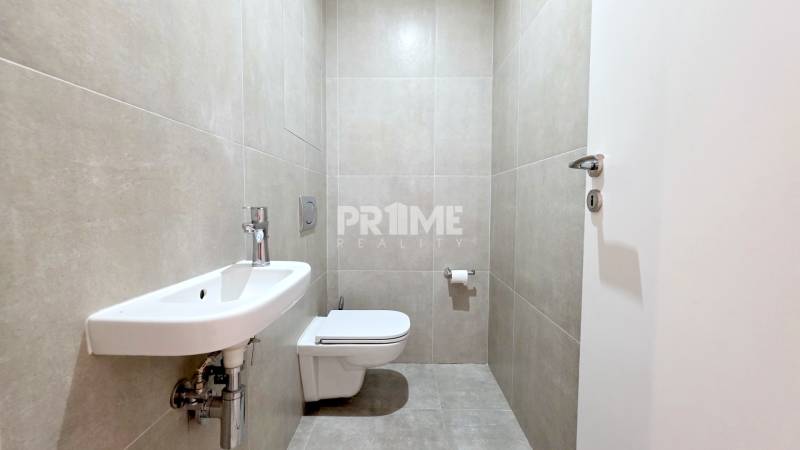 Bathroom in a 2-room apartment with a toilet, sink, and tiles in neutral shades.