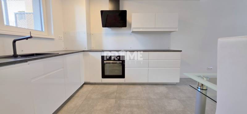A kitchen in a 2-room apartment with white cabinets and a black sink.