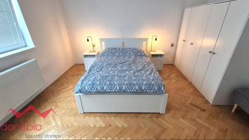 Bedroom with a bed, nightstands, and a wardrobe, floor with wood decor.