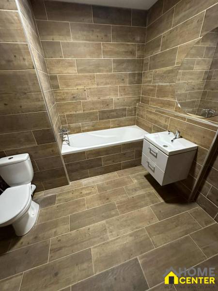 Studio apartment: Bathroom with a bathtub, toilet, and sink, floor with wood decor.