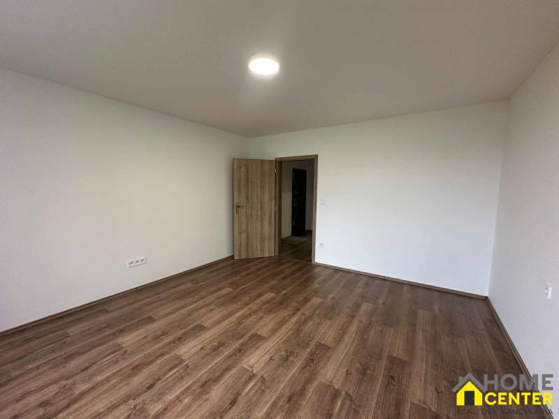 Two-room apartment with white walls and wood-patterned flooring, open doors.