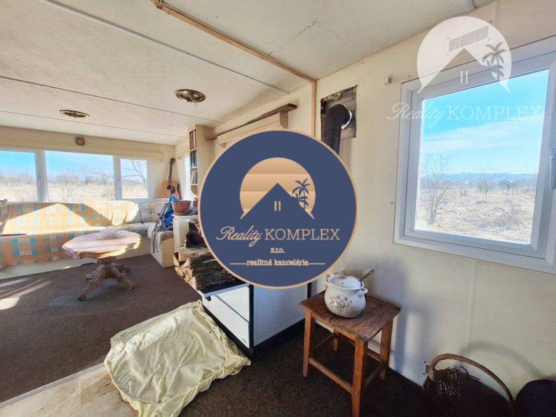 Interior with a sofa, guitar, window overlooking agricultural and forest land.