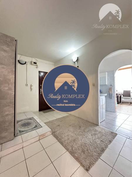 Interior of a 1-room apartment with white tiles and a carpet at the entrance.