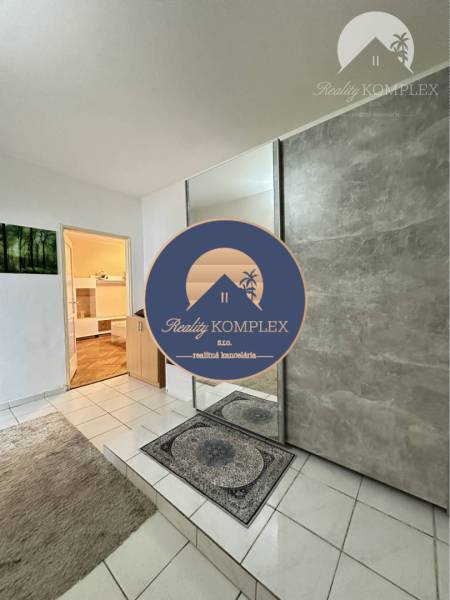 Entrance hall with tiled flooring, mirrored doors, view into a room with wood-patterned flooring.