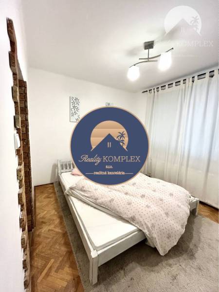 Bedroom with a white bed, light, and a floor with a wooden decor in a 3-room apartment.