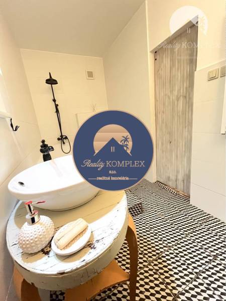 A bathroom in a 3-room apartment with original black and white mosaic and a freestanding sink.