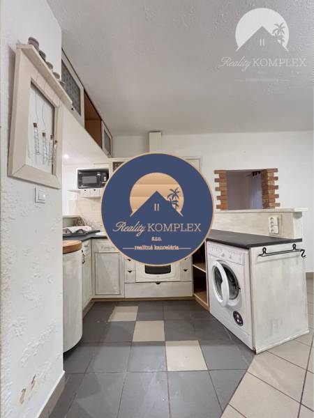 A kitchen in a 3-room apartment with a built-in oven and dishwasher, with ceramic tiles.