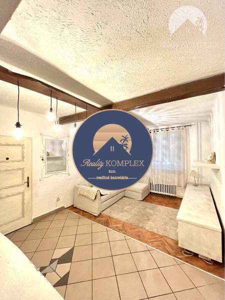 Living room with wood-patterned flooring in a 3-room apartment, white sofa and curtains.