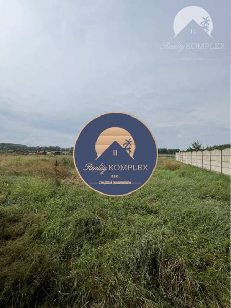 Residential plots in Iža with a view of the surrounding countryside and a fence.