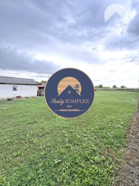 A garden at a family house in Komárno with a lawn under the clouds.