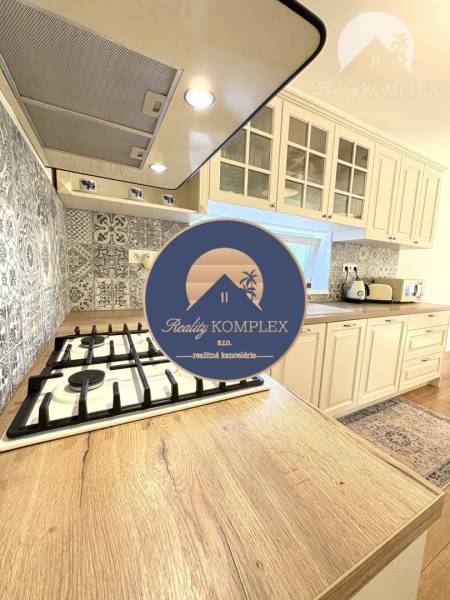 A kitchen in a family house with a wood-patterned floor and patterned tiles.