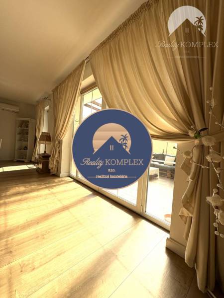 A bright room in a family house, large windows, curtains, and a wooden decor floor.