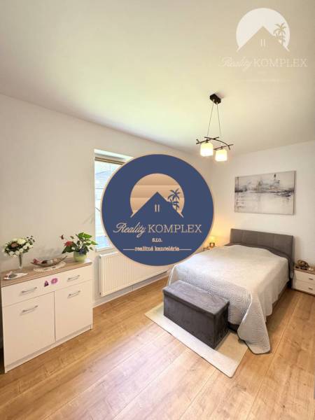 Bedroom in a family house with a bed, dresser, and wooden decor flooring.