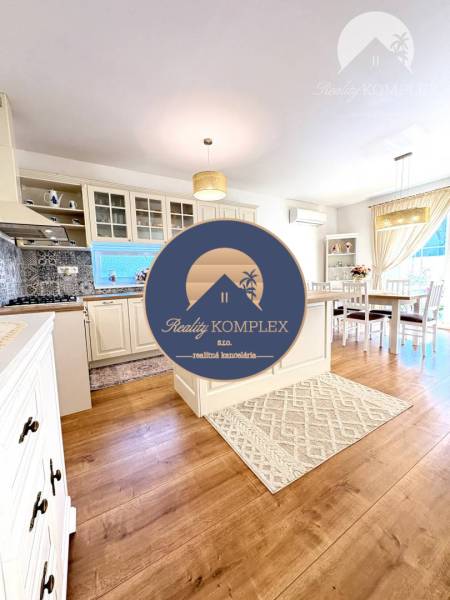 A kitchen with a dining area in a family house, wooden decor flooring, cream cabinets.