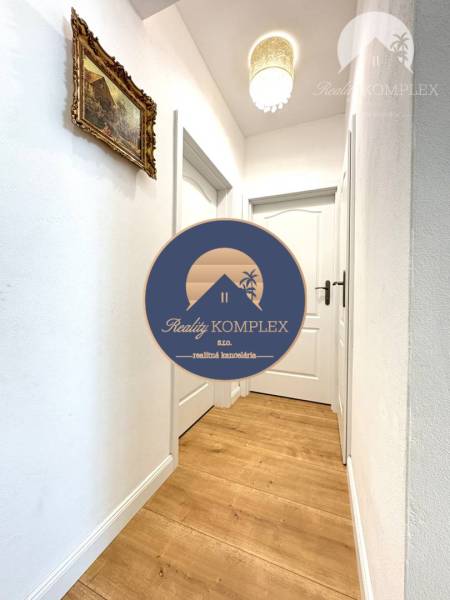 A hallway in a family house with wallpaper and a wooden decor floor.