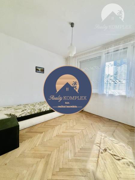 A bright living room in a two-room apartment with a sofa and wood-patterned flooring.