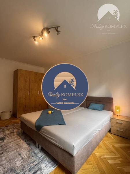 A bedroom in a one-room apartment with light, a wardrobe, and a bed on the floor with a wooden decor.