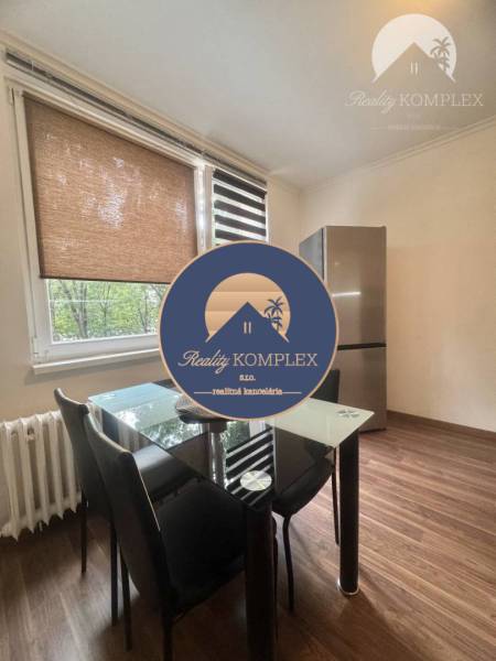 Dining area with a glass table and a refrigerator, 1-room apartment, floor with wood decor.