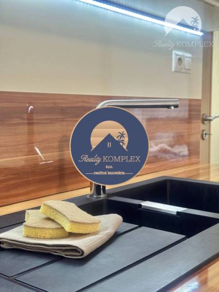 Kitchen sink with a black surface, floor with a wooden decor in a studio apartment.