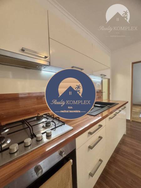 A kitchen unit in a one-room apartment with a wooden decor floor and a cooktop.