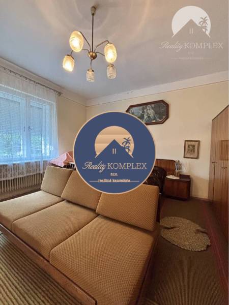Living room in a family house with a sofa, chandelier, and light curtain on the window.