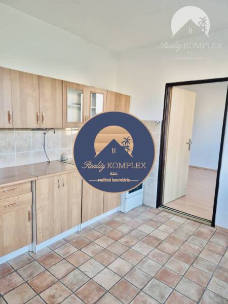 Kitchen in a studio apartment with tiled flooring and wooden decor cabinets.