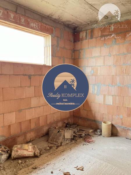 An unfinished room in a family house with brick walls and construction materials.