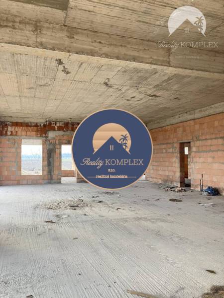 A spacious interior of an unfinished family house with visible bricks and a concrete ceiling.