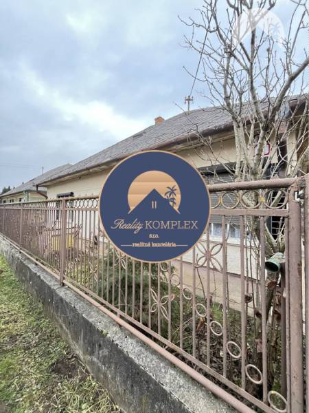 A family house in Strekov behind a metal fence, surrounded by trees and a peaceful environment.