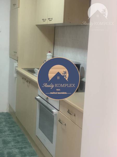 A kitchen with beige cabinets and white appliances in the space of warehouses and halls.