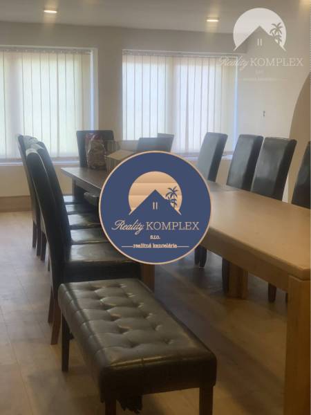 A room with a table and upholstered chairs, a floor with a wooden decor.