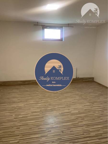 Empty room with wood-patterned flooring, small window, bright walls.