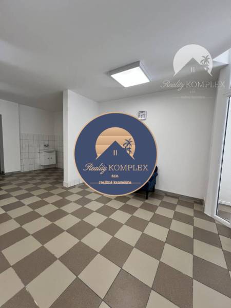 Commercial premises with tiled floor and sink, seating in the corner of the room.