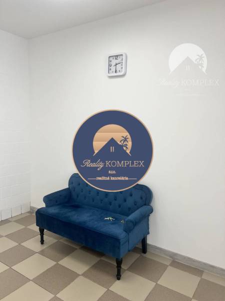 A blue sofa with a tiled floor and a wall clock in a commercial space.