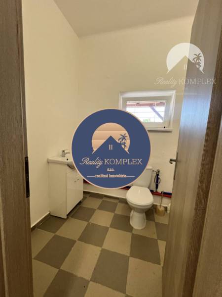 A toilet with a sink and a window in commercial premises with a simple design.