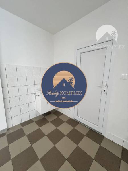 Commercial space with a checkered floor and white walls, featuring a door and a sink.