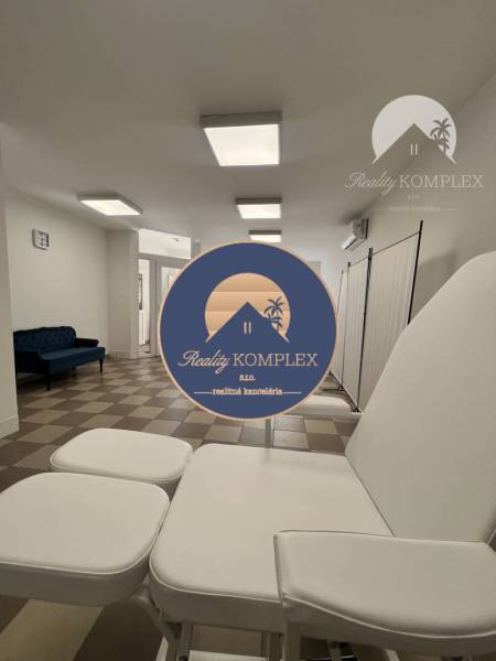 Commercial space with an armchair and a dark blue sofa on a white-brown floor.