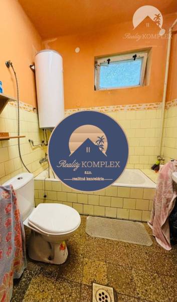 Bathroom with a bathtub and toilet, tiles on the walls, and window ventilation.