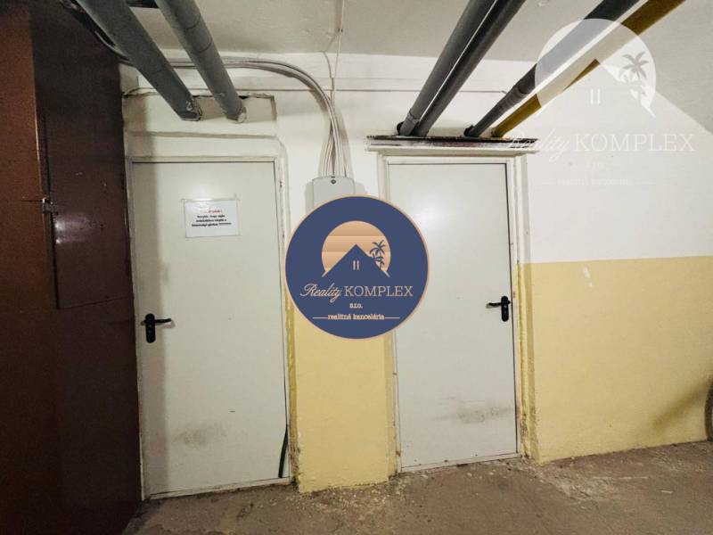 Two white doors in the basement of a 3-room apartment with pipes on the ceiling.
