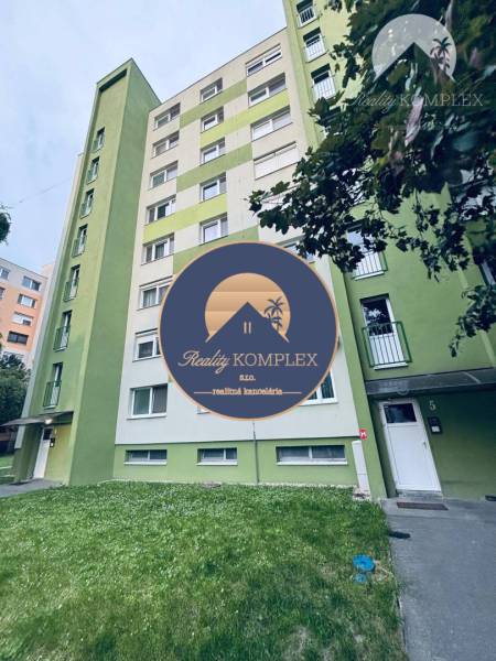 Apartment building in Veľký Meder with an access walkway to the entrance, surrounded by greenery.