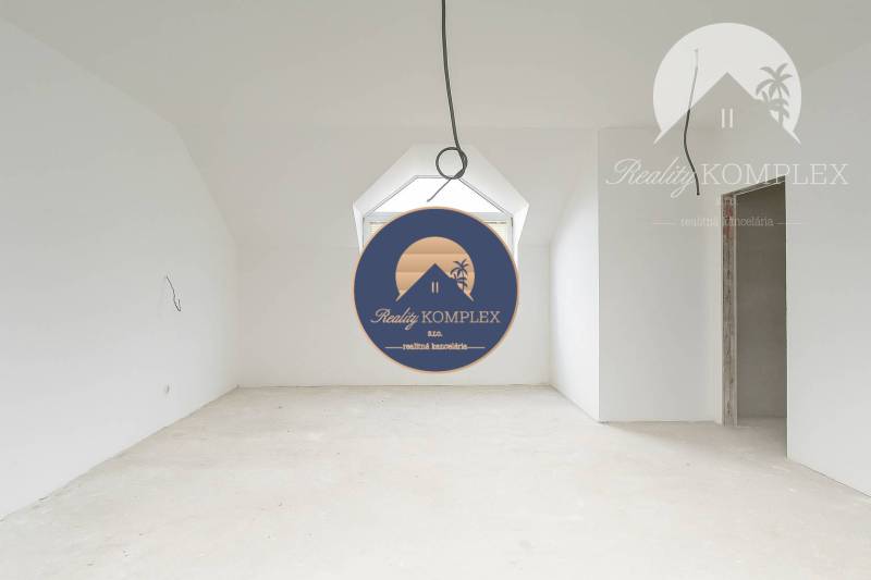 A spacious unfurnished room in a family house with a sloped ceiling and a large window.