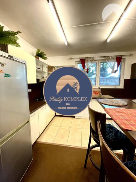 A kitchen in a family house with white furniture, a refrigerator, and a dining table.