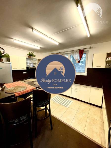 Interior of a family house with a kitchen, bar stools, and a wooden decor floor.