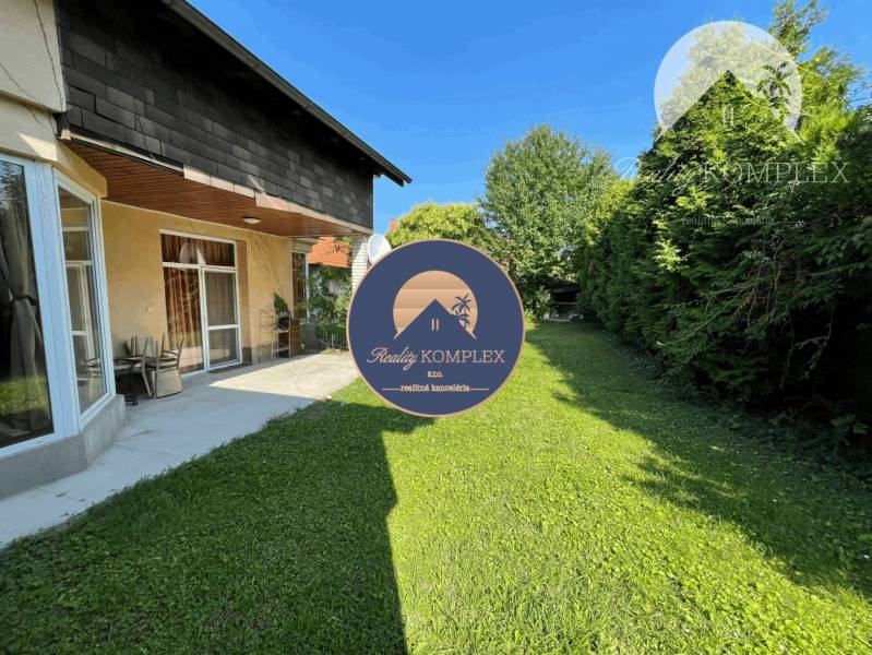 A family house in Dunajská Streda with a lawn and a terrace surrounded by trees.