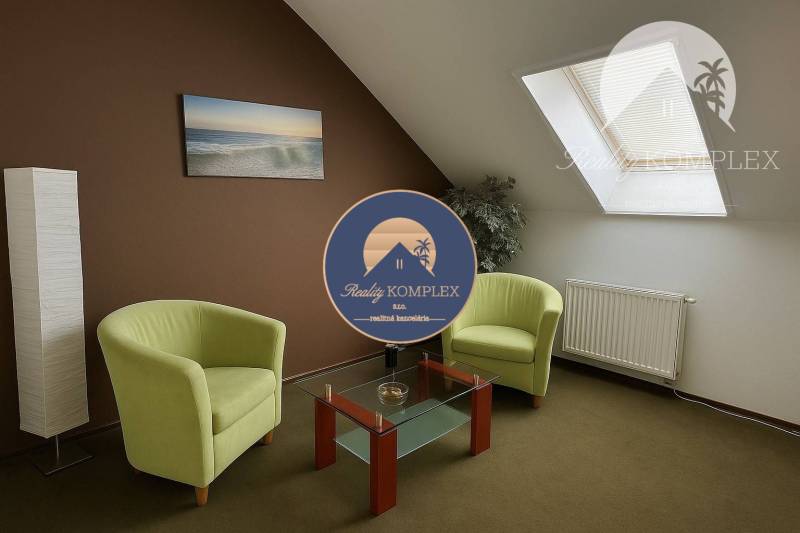 A lit room in a family house with two green armchairs and a glass table.