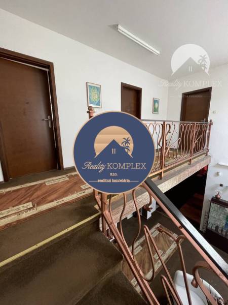 Interior of a family house with a brown carpet and metal railing on the staircase.